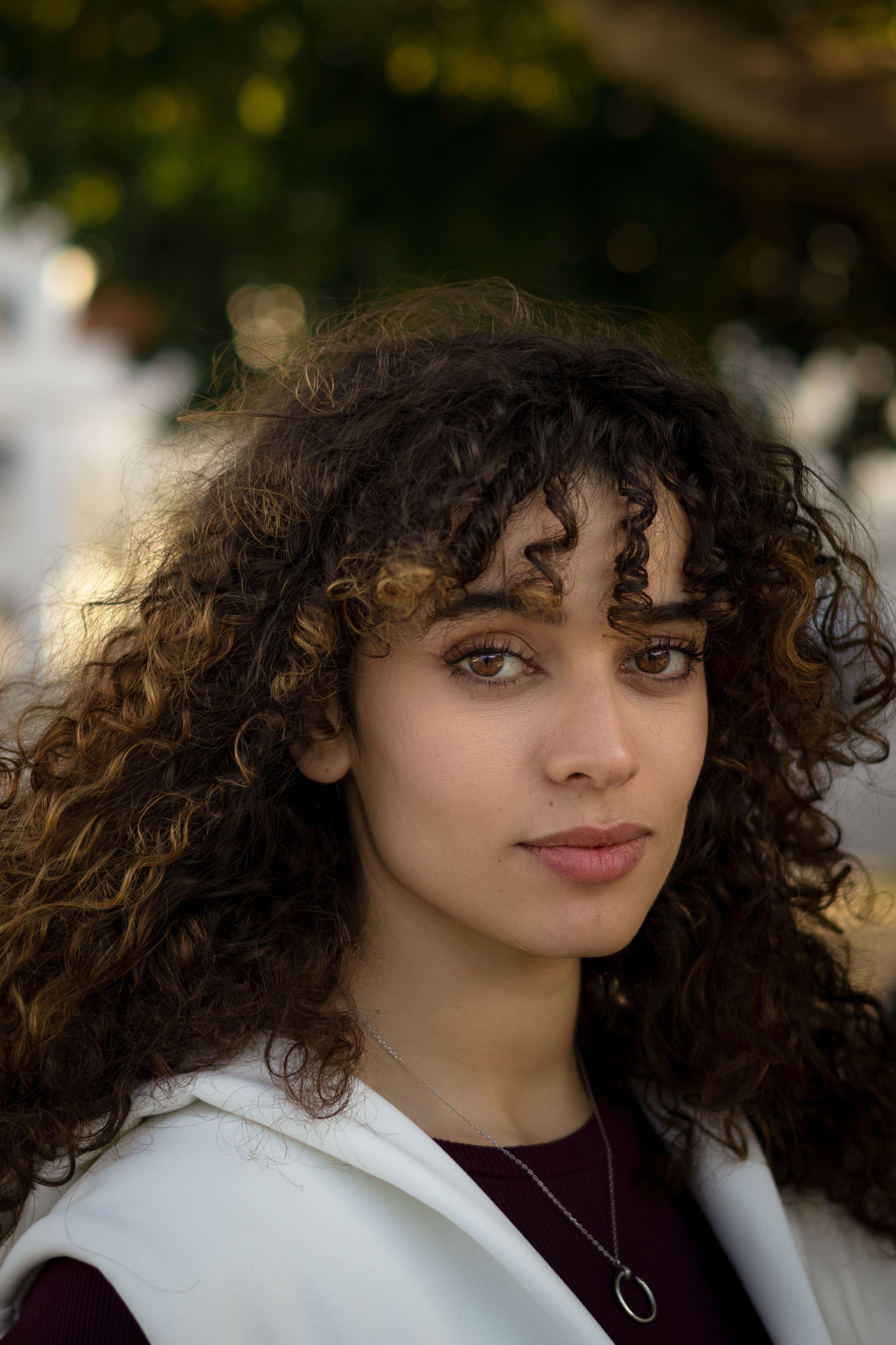 Mulher de cabelo cacheado castanho com volume, fios definidos emoldurando o rosto